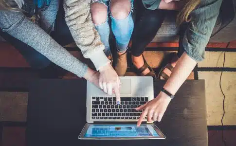 three person pointing the silver laptop computer