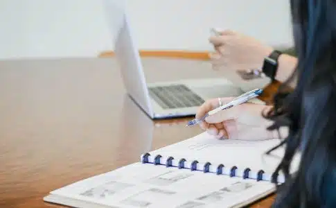 person holding pen writing on paper